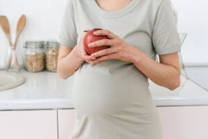 crop pregnant woman with apple